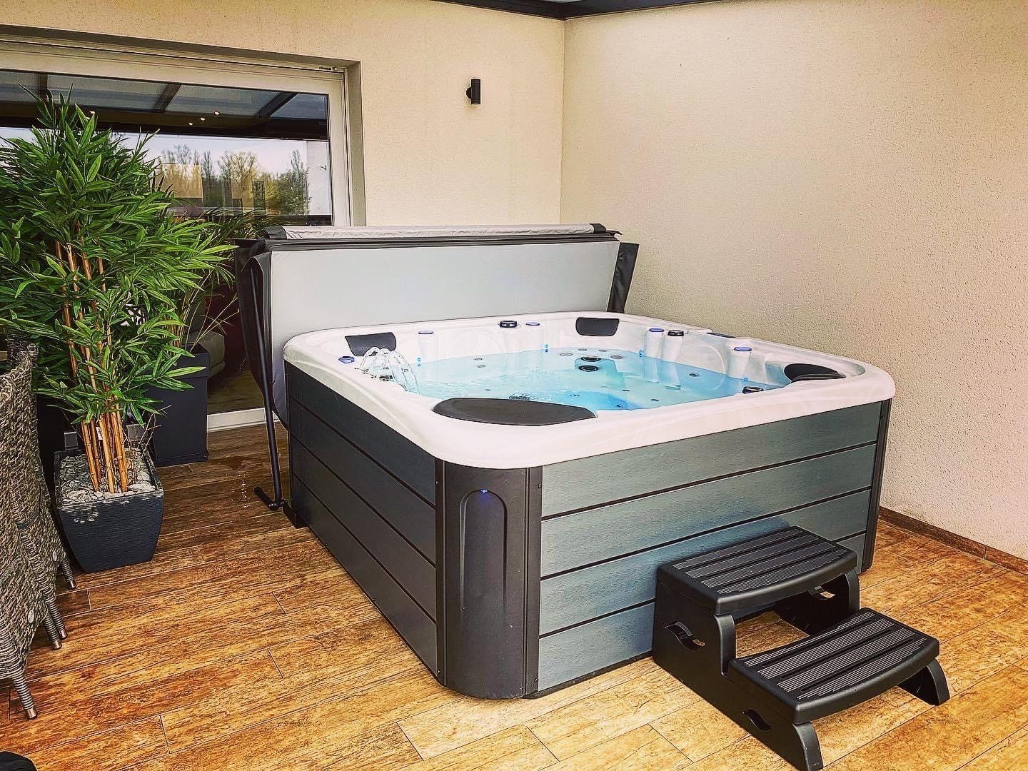 Un bain à remous est installé sur une terrasse à côté d'une fenêtre.