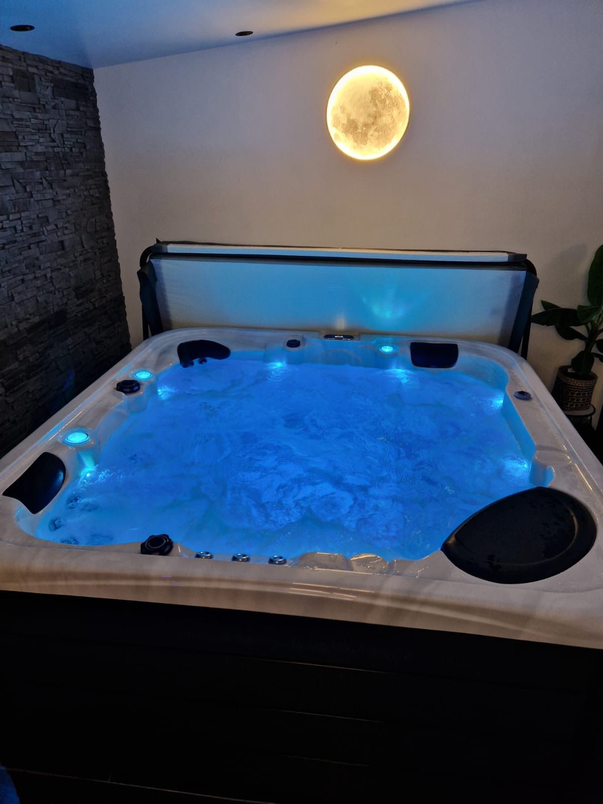 Un grand bain à remous est installé dans une pièce avec une pleine lune en arrière-plan.