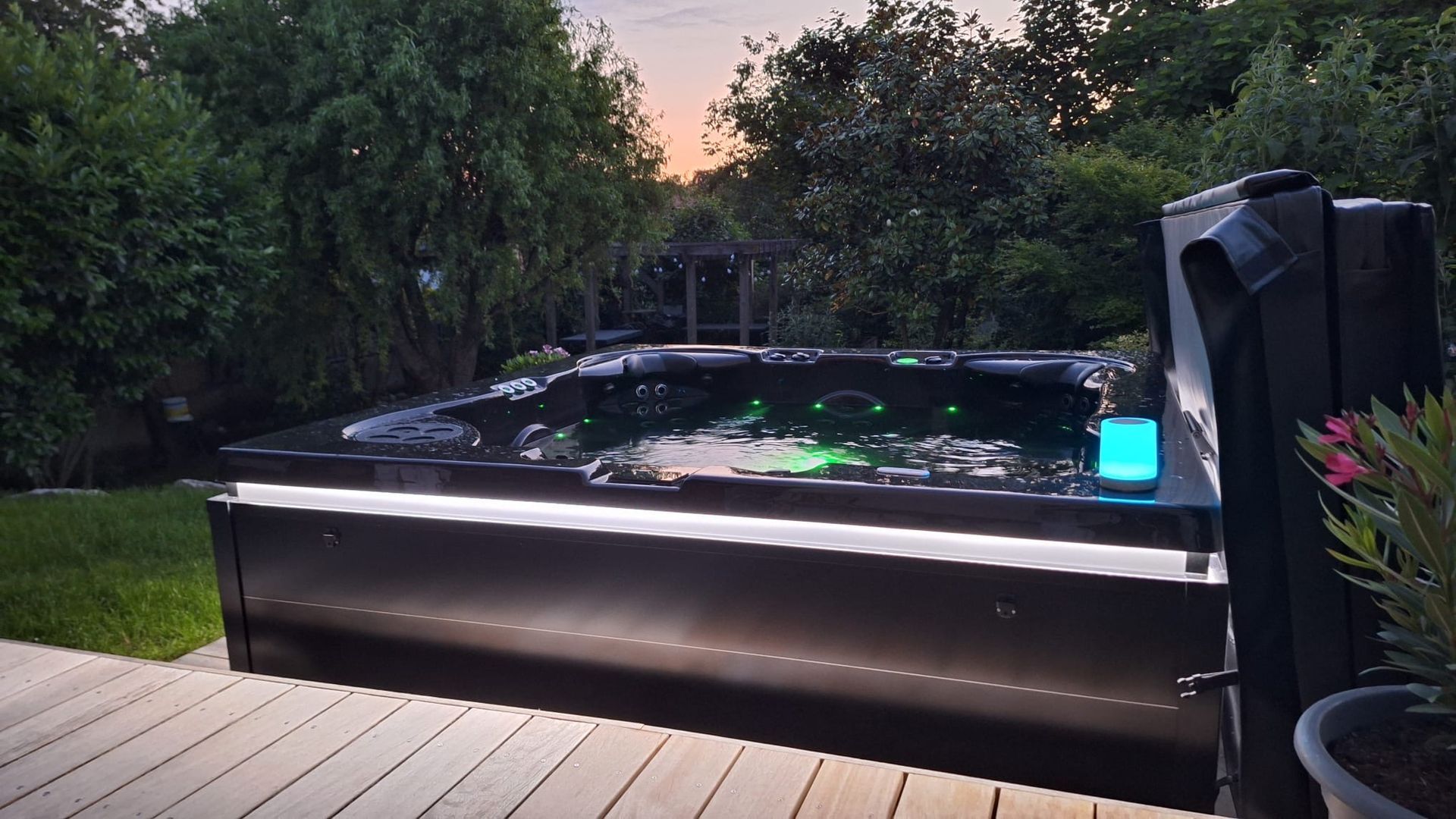 Un jacuzzi noir est posé sur une terrasse en bois dans une cour arrière.