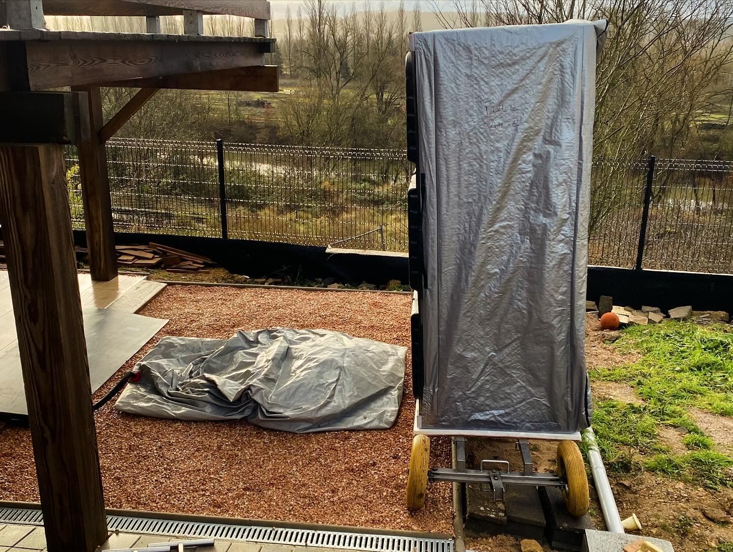 Un réfrigérateur est emballé dans du plastique et posé sur un chariot dans une cour arrière.
