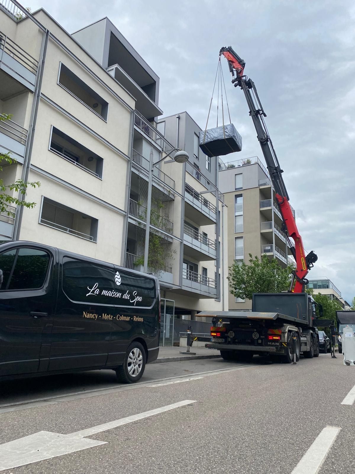 Une camionnette est garée sur le bord de la route devant un immeuble.