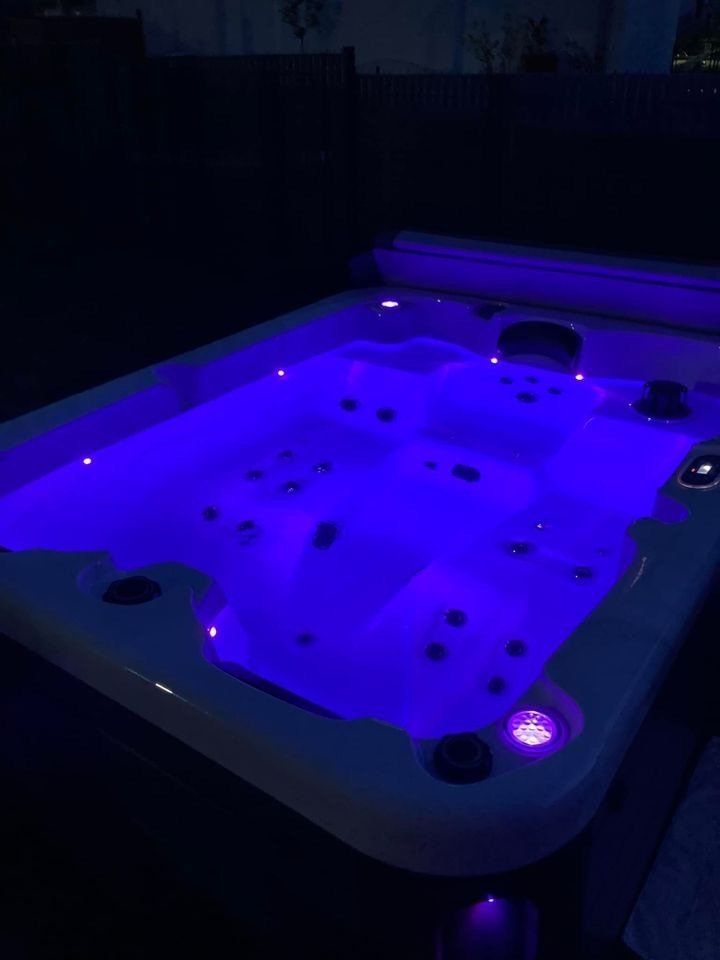Un bain à remous est éclairé par des lumières bleues la nuit.