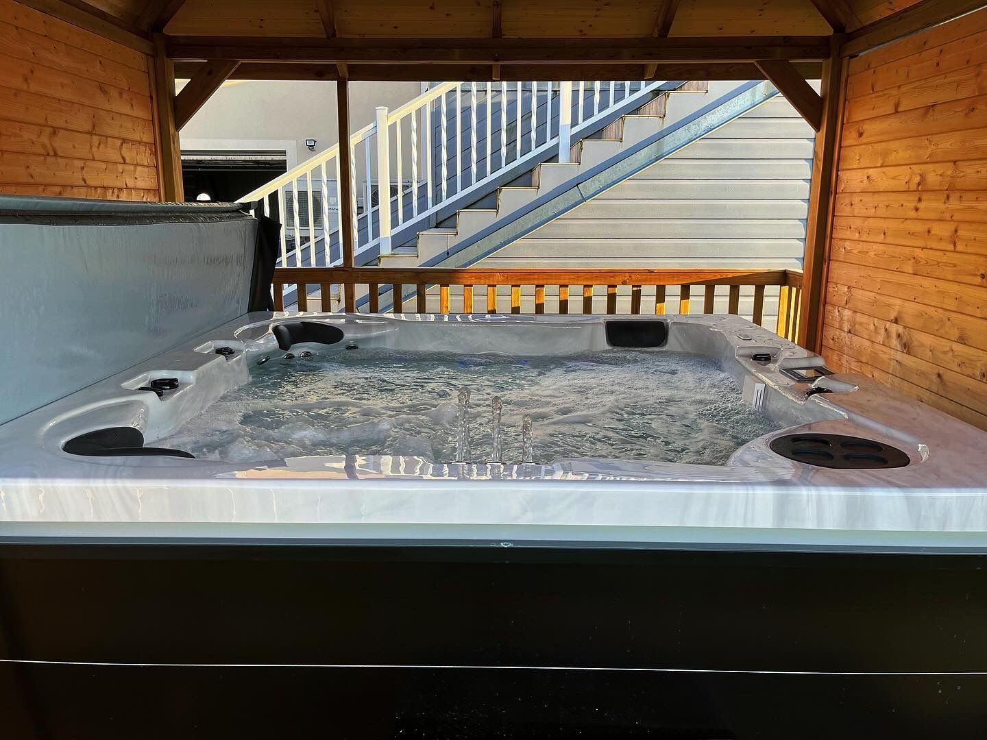 Un bain à remous est assis sous une structure en bois avec des escaliers en arrière-plan.