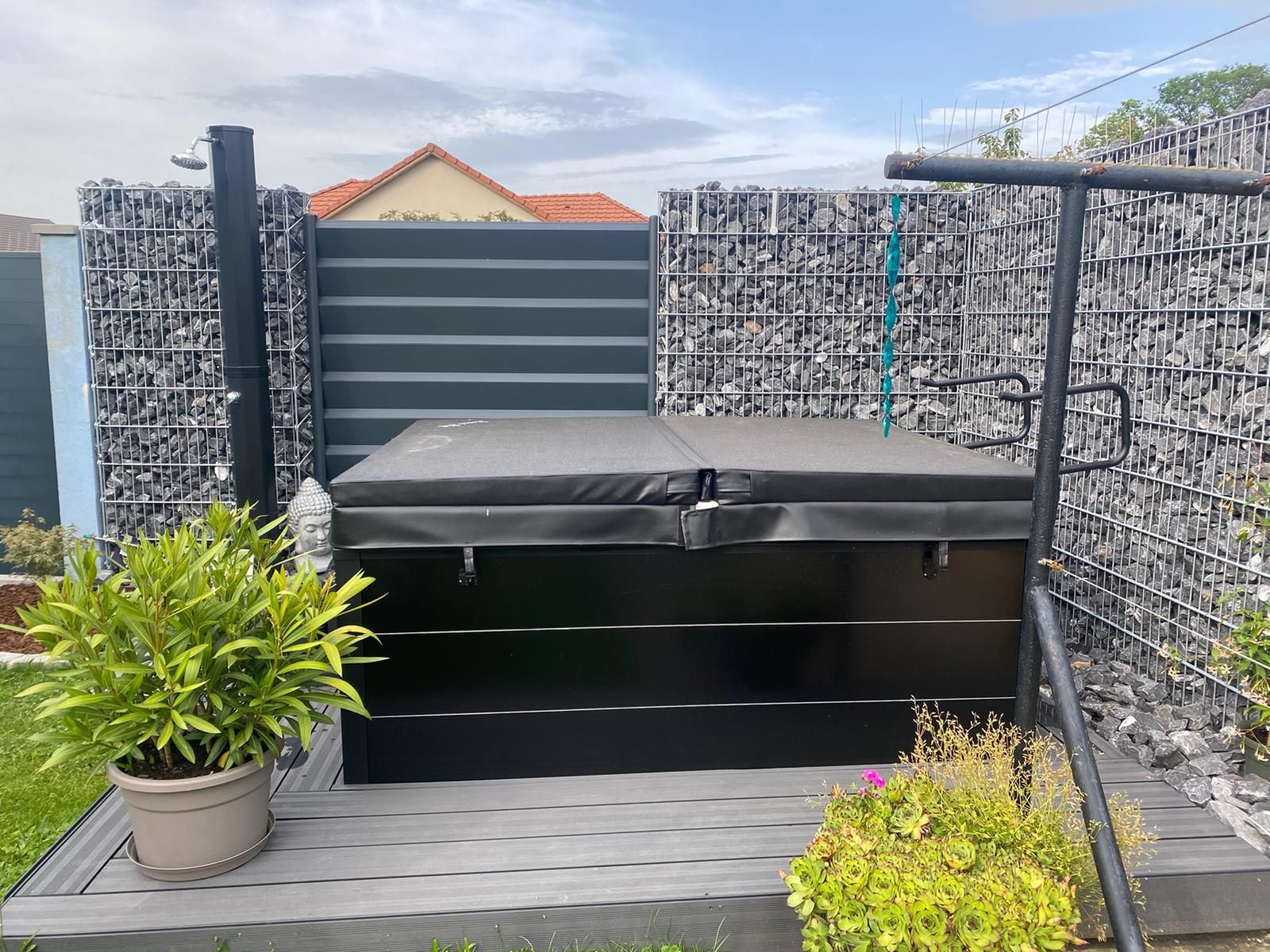 Un bain à remous est posé sur une terrasse en bois à côté d'une clôture.