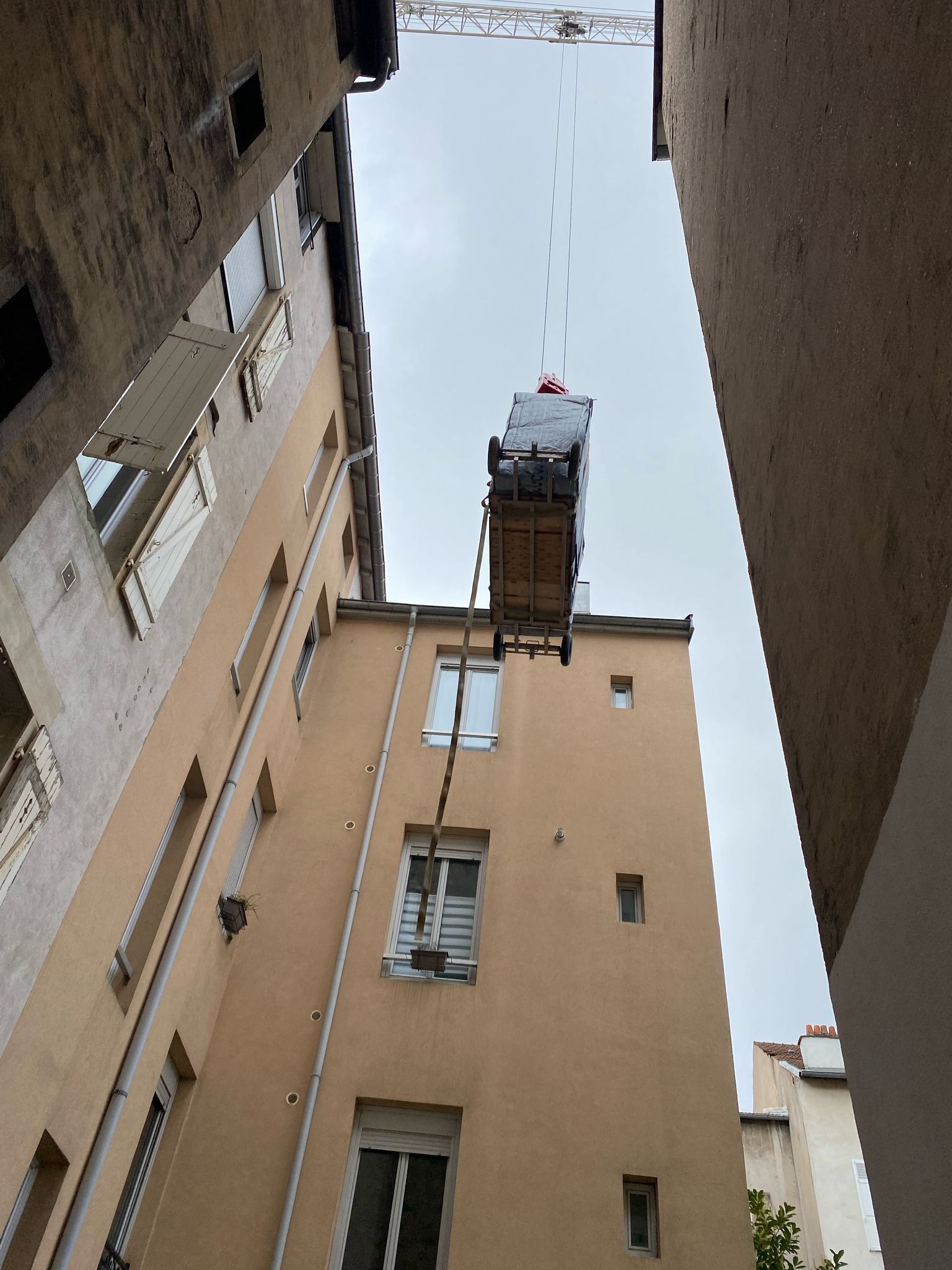 Une grue soulève un piano dans un bâtiment