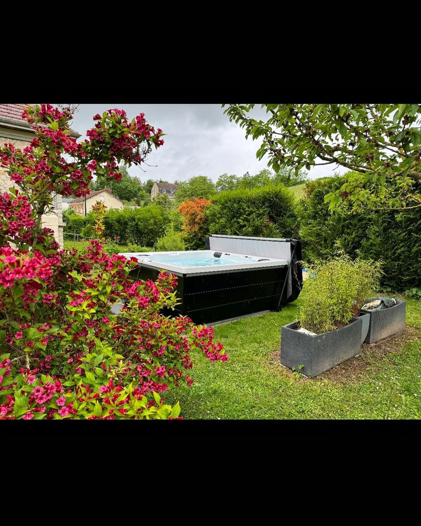 Un bain à remous est assis au milieu d'un jardin entouré de fleurs.
