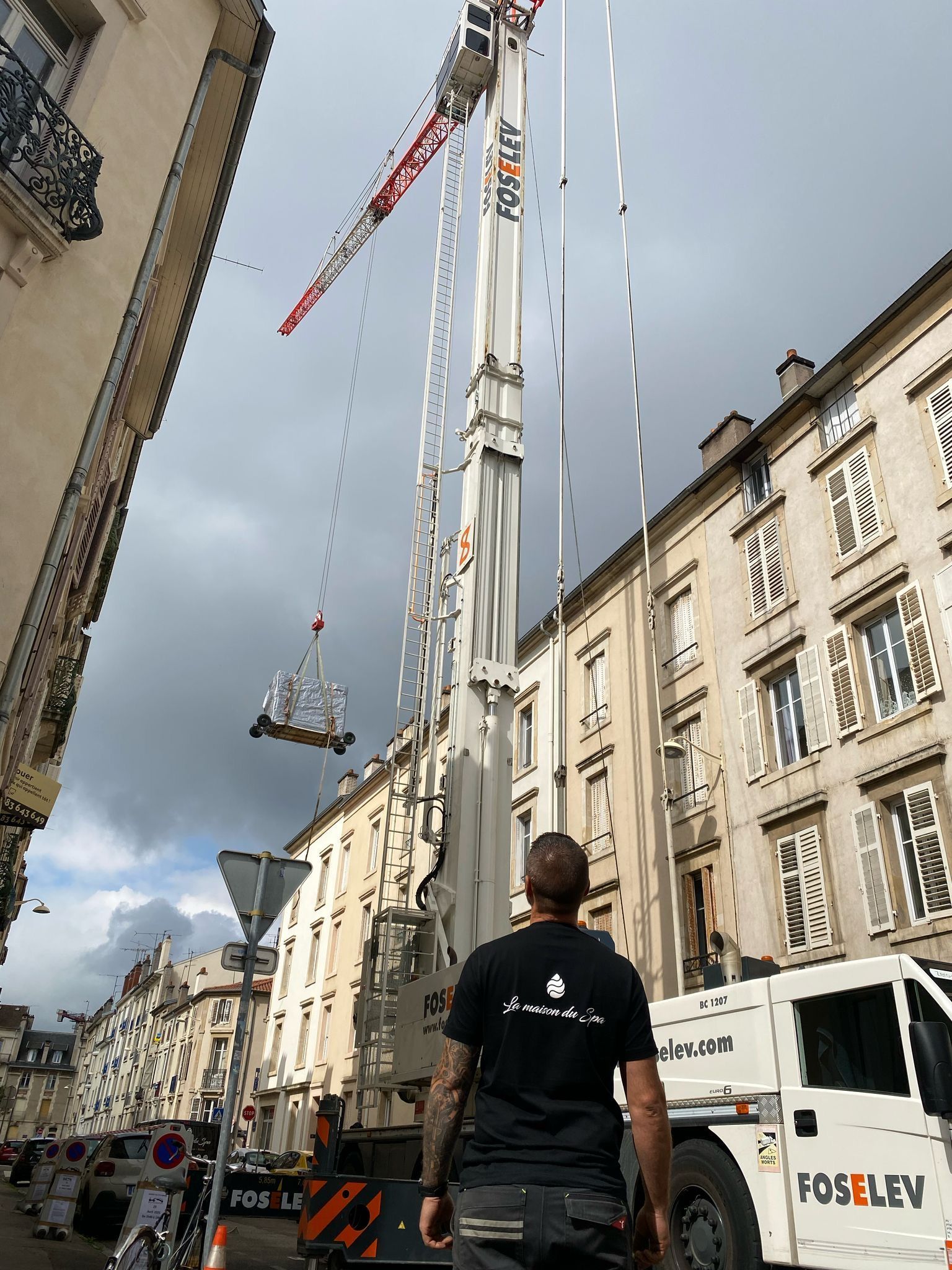 Un homme se tient devant une grue dans une ville.