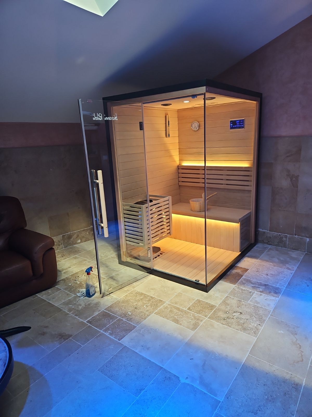 Un sauna est assis au milieu d'une pièce à côté d'une chaise.