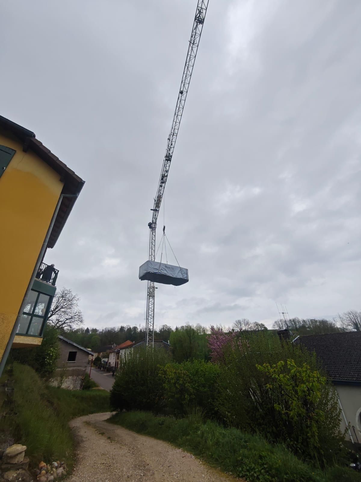 Une grue soulève un gros morceau de métal dans les airs.
