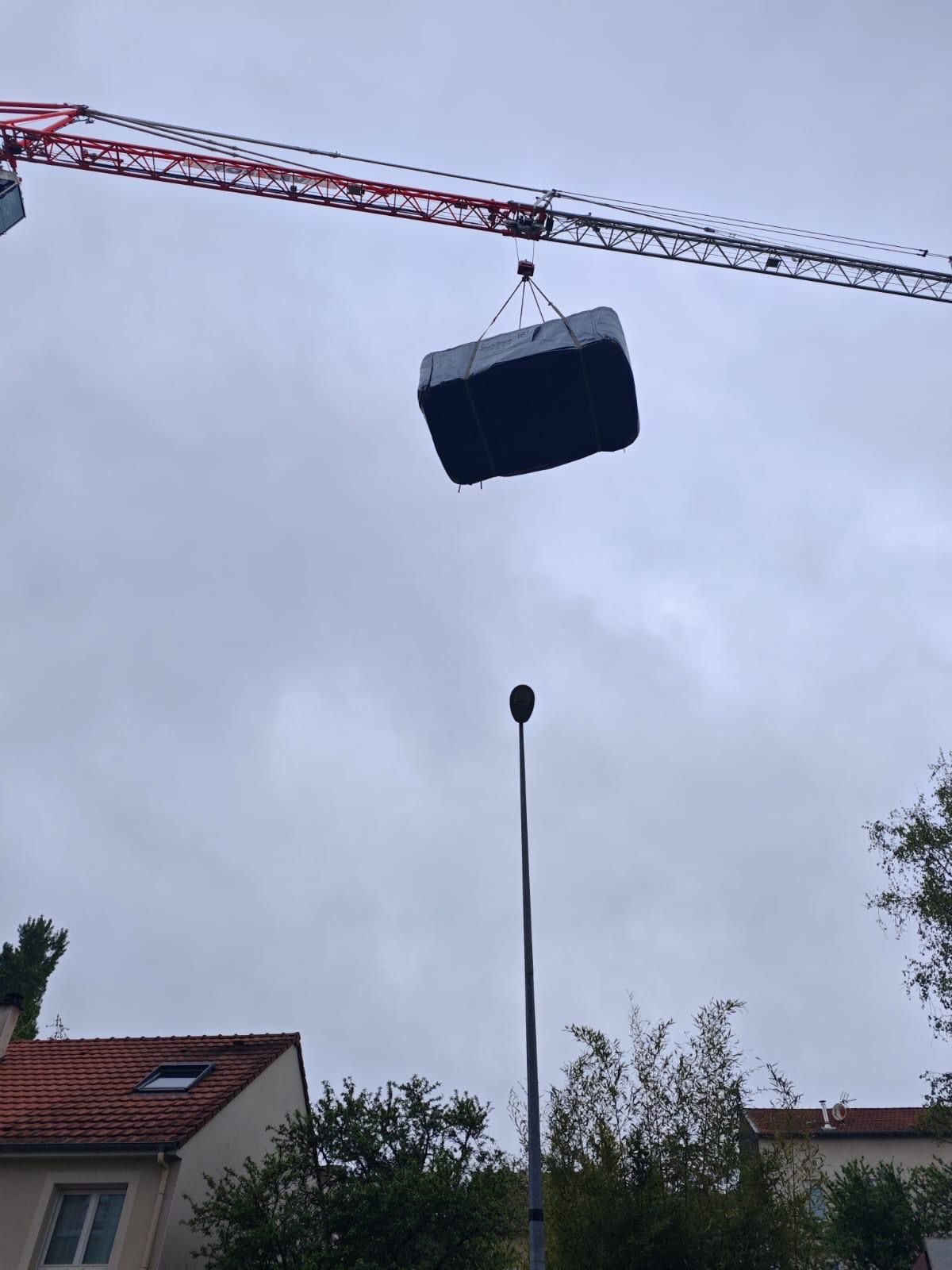 Une grue soulève une grande boîte noire dans les airs