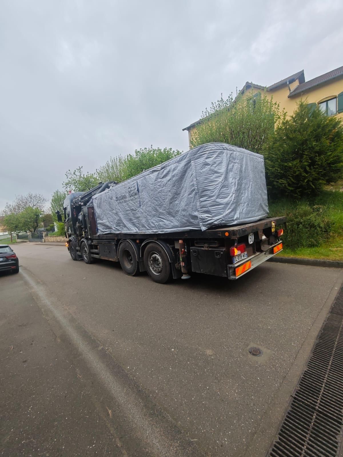 Un camion est recouvert d'une bâche et roule dans une rue.