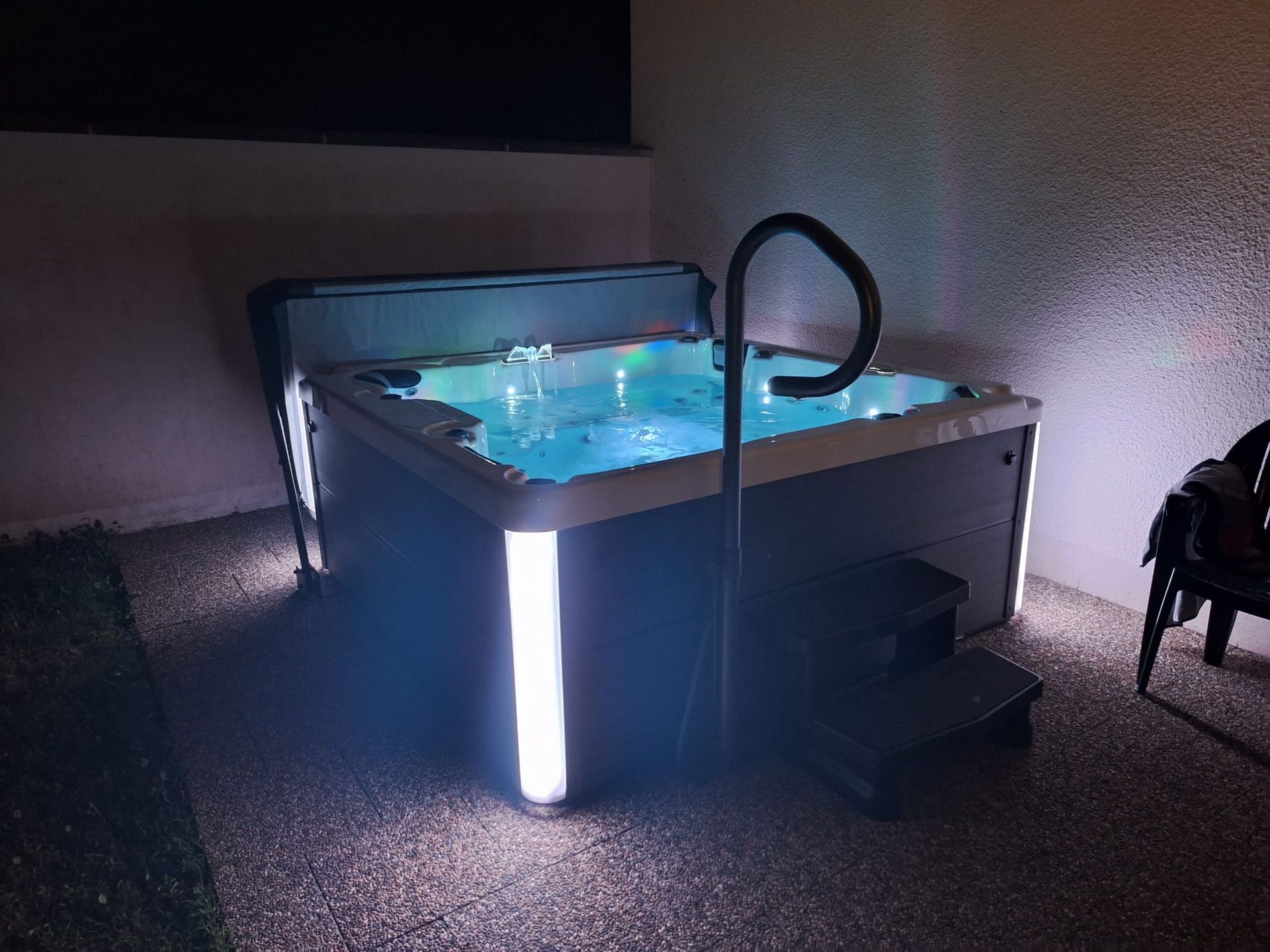 Un bain à remous avec des escaliers menant à celui-ci est éclairé la nuit.