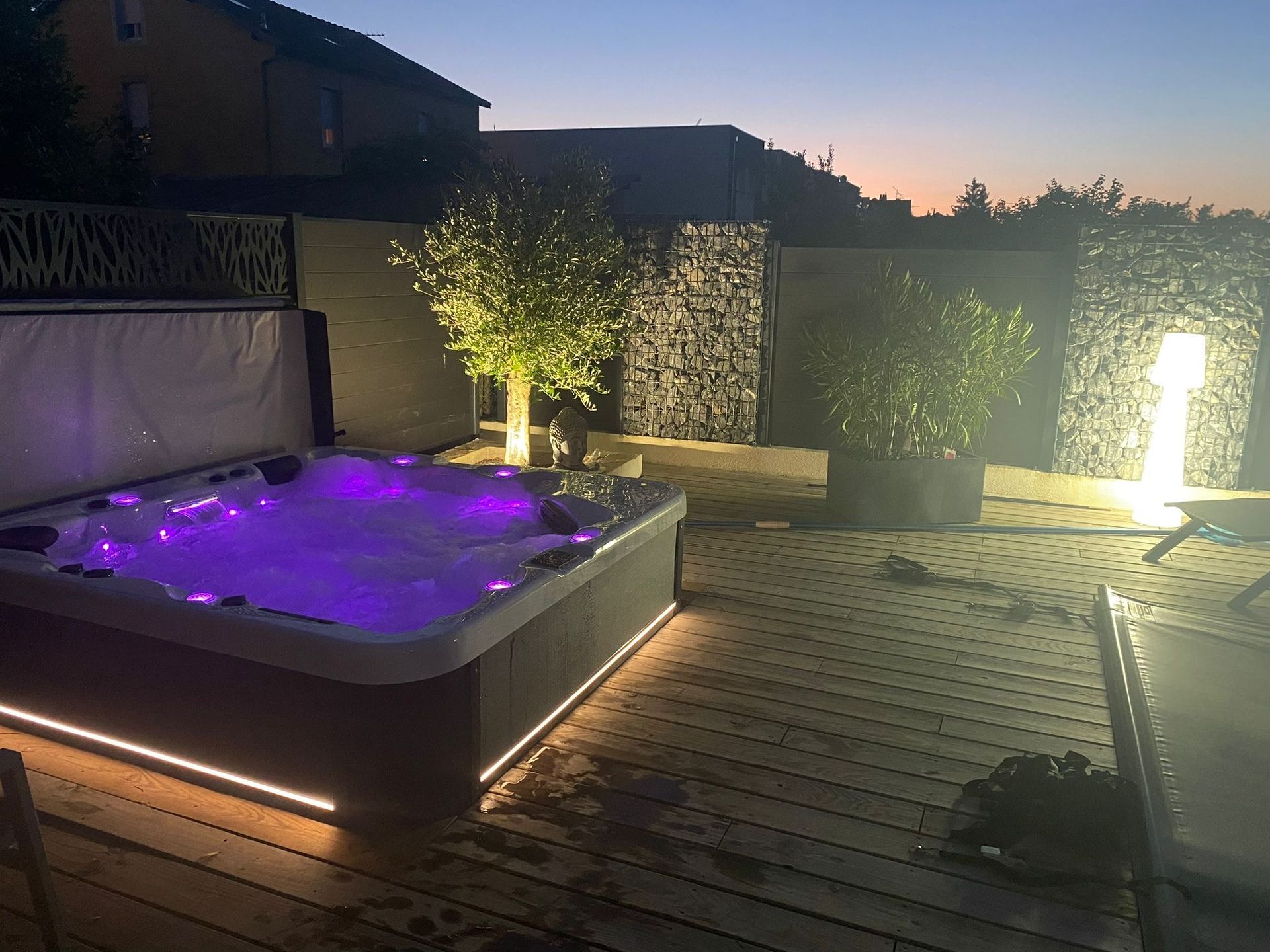 Un jacuzzi est éclairé la nuit sur une terrasse.