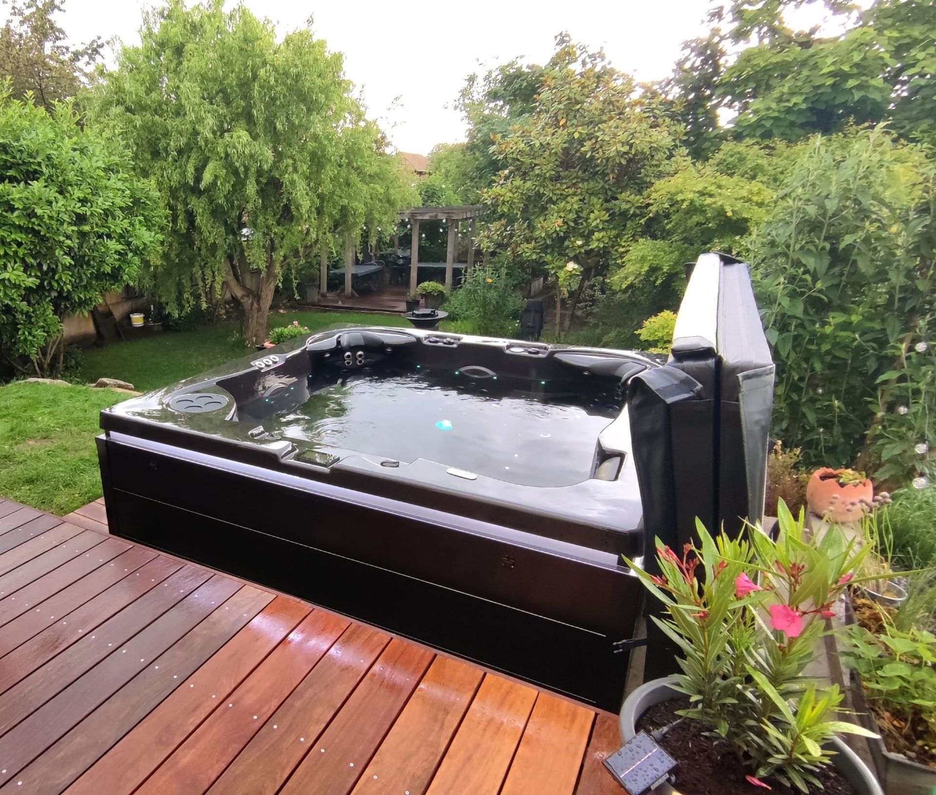 Un jacuzzi noir est posé sur une terrasse en bois