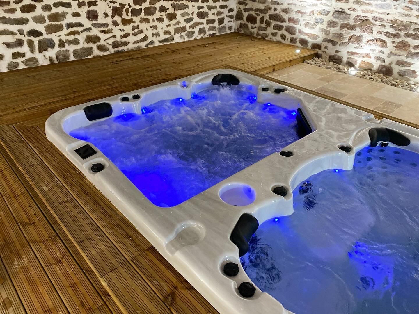 Un bain à remous est posé sur une terrasse en bois dans une pièce.