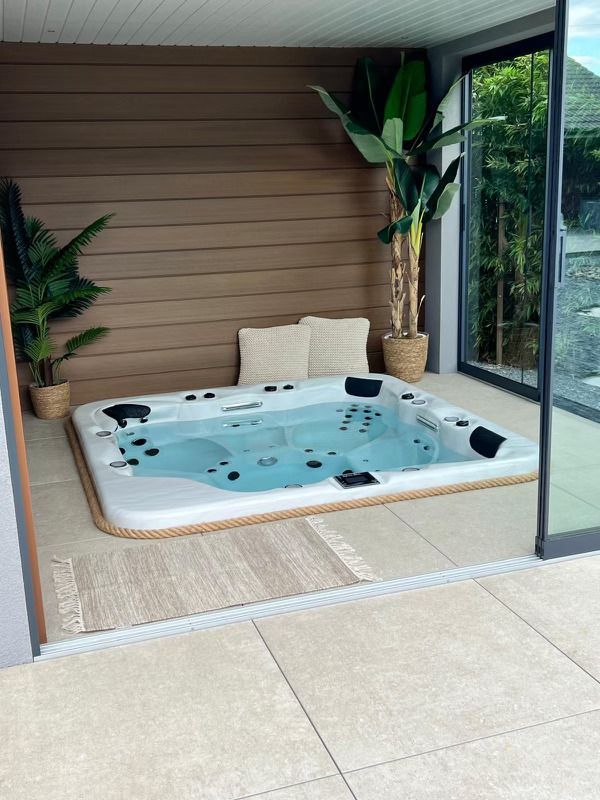 Un grand bain à remous est installé dans une pièce à côté d'une fenêtre.