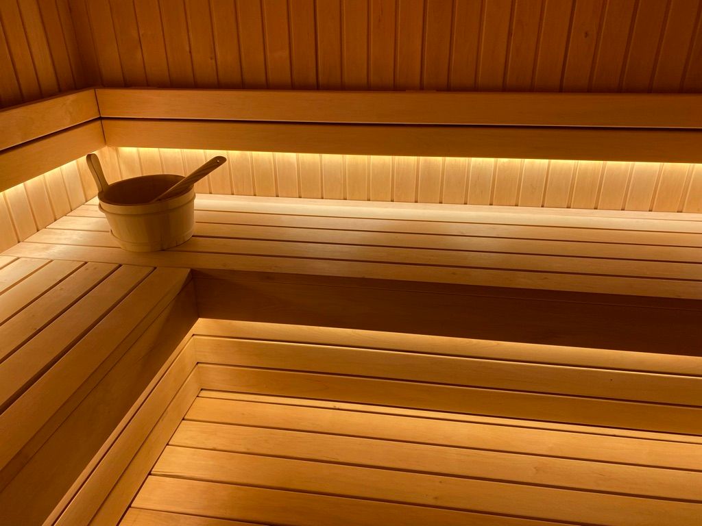Un sauna en bois avec un seau et une cuillère sur le banc.