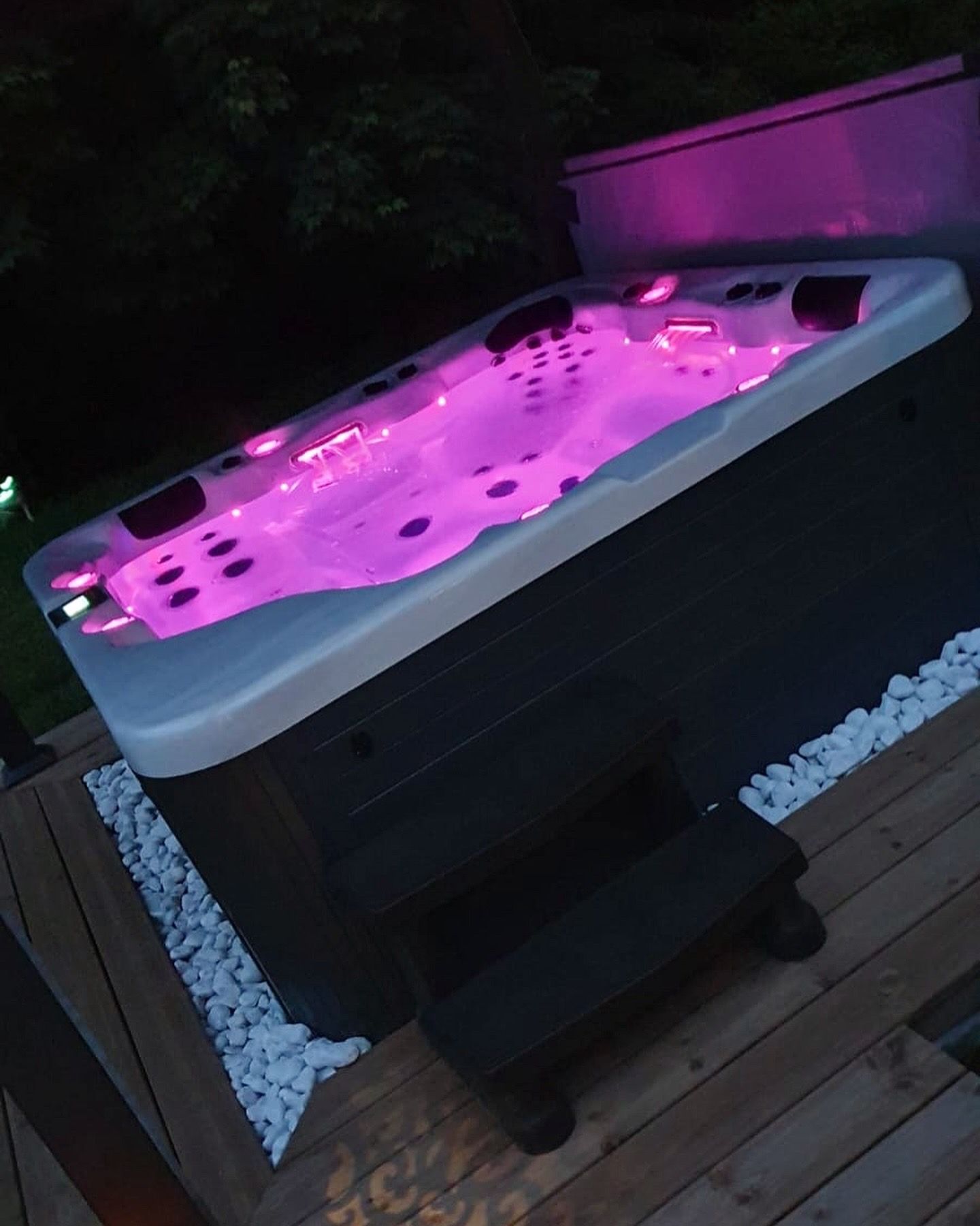 Un jacuzzi avec des lumières violettes est sur une terrasse