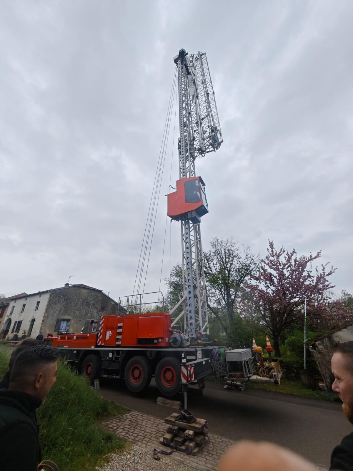 Une grande grue rouge est assise sur le toit d'un camion.