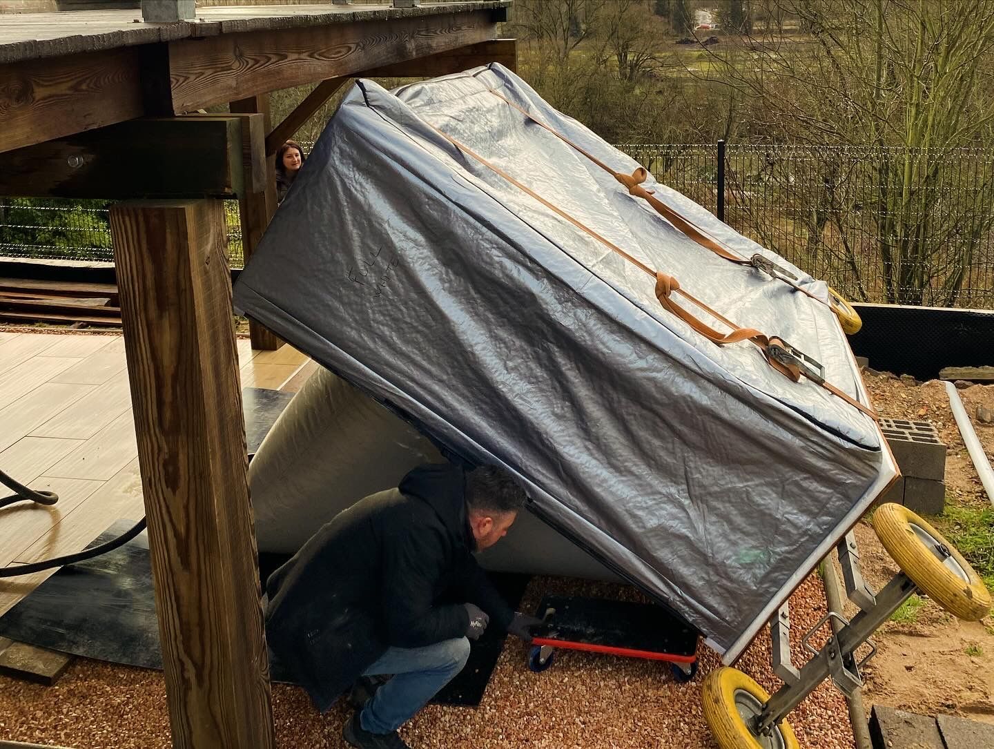 Un homme est agenouillé sous une bâche sur un toit.