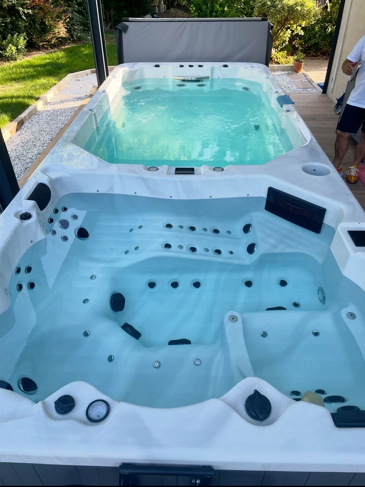 Un spa de nage à deux zones avec une zone de baignade et une section bain à remous, remplie d'eau, à l'extérieur.