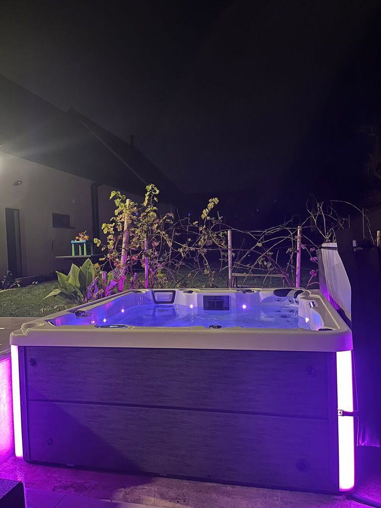 Un bain à remous est éclairé la nuit avec des lumières violettes.