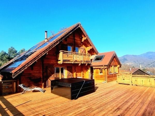 Une grande maison en bois avec un jacuzzi sur la terrasse.