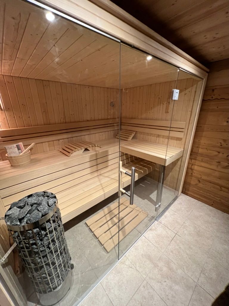 Un sauna en bois avec une porte vitrée et un banc en bois.