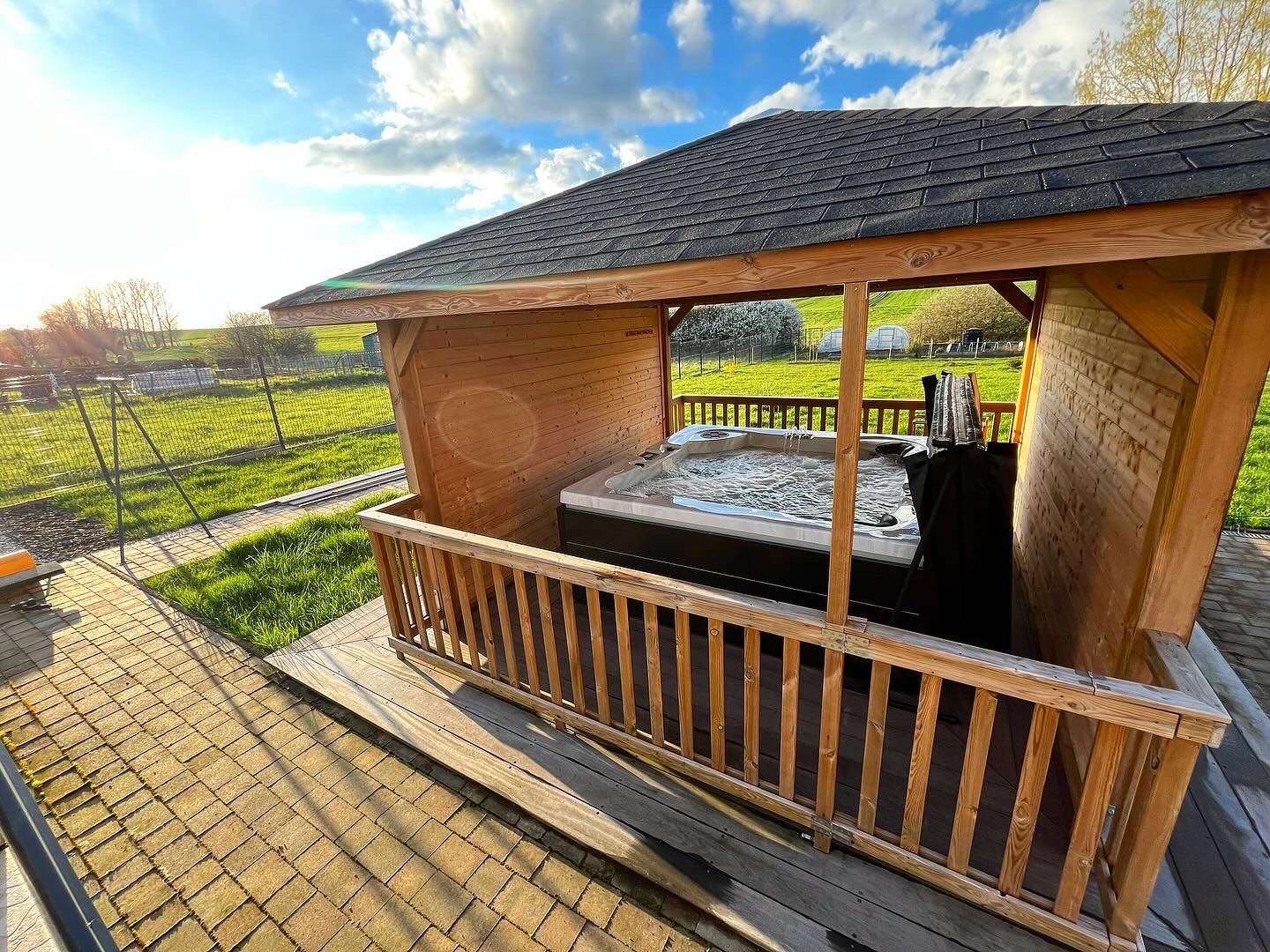 Un bain à remous est installé sous un gazebo en bois.