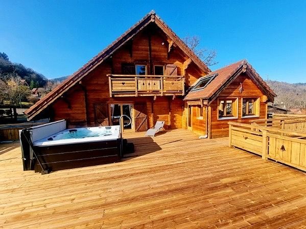 Une grande maison en bois avec un jacuzzi sur la terrasse.