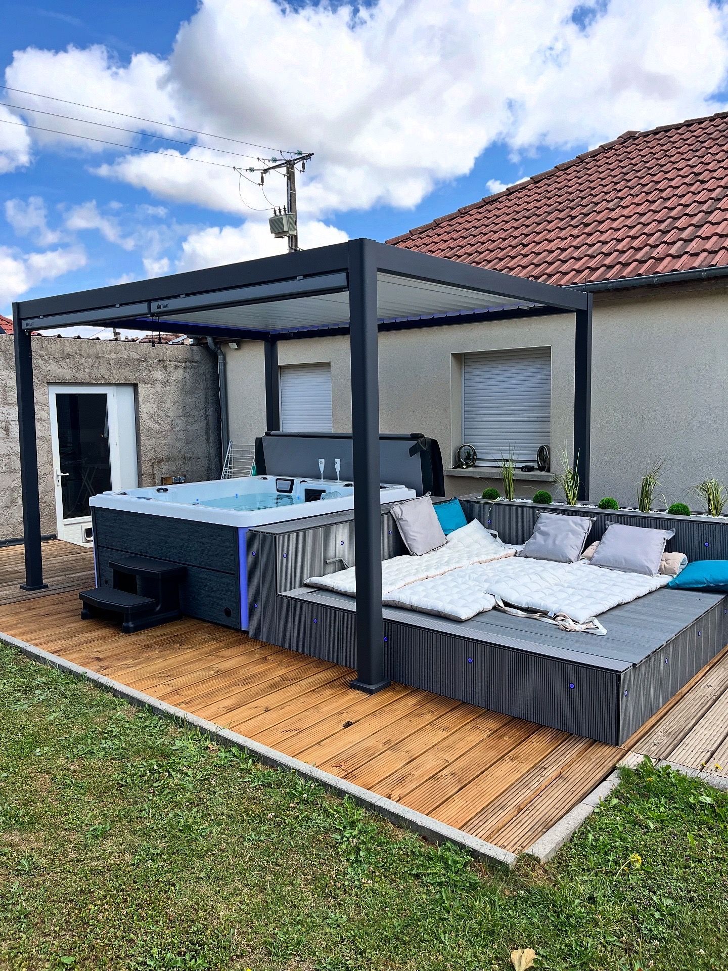 Bain à remous et coin salon sous une pergola dans une cour arrière.