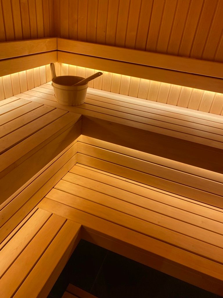 Un sauna en bois avec un seau et une cuillère sur le banc.