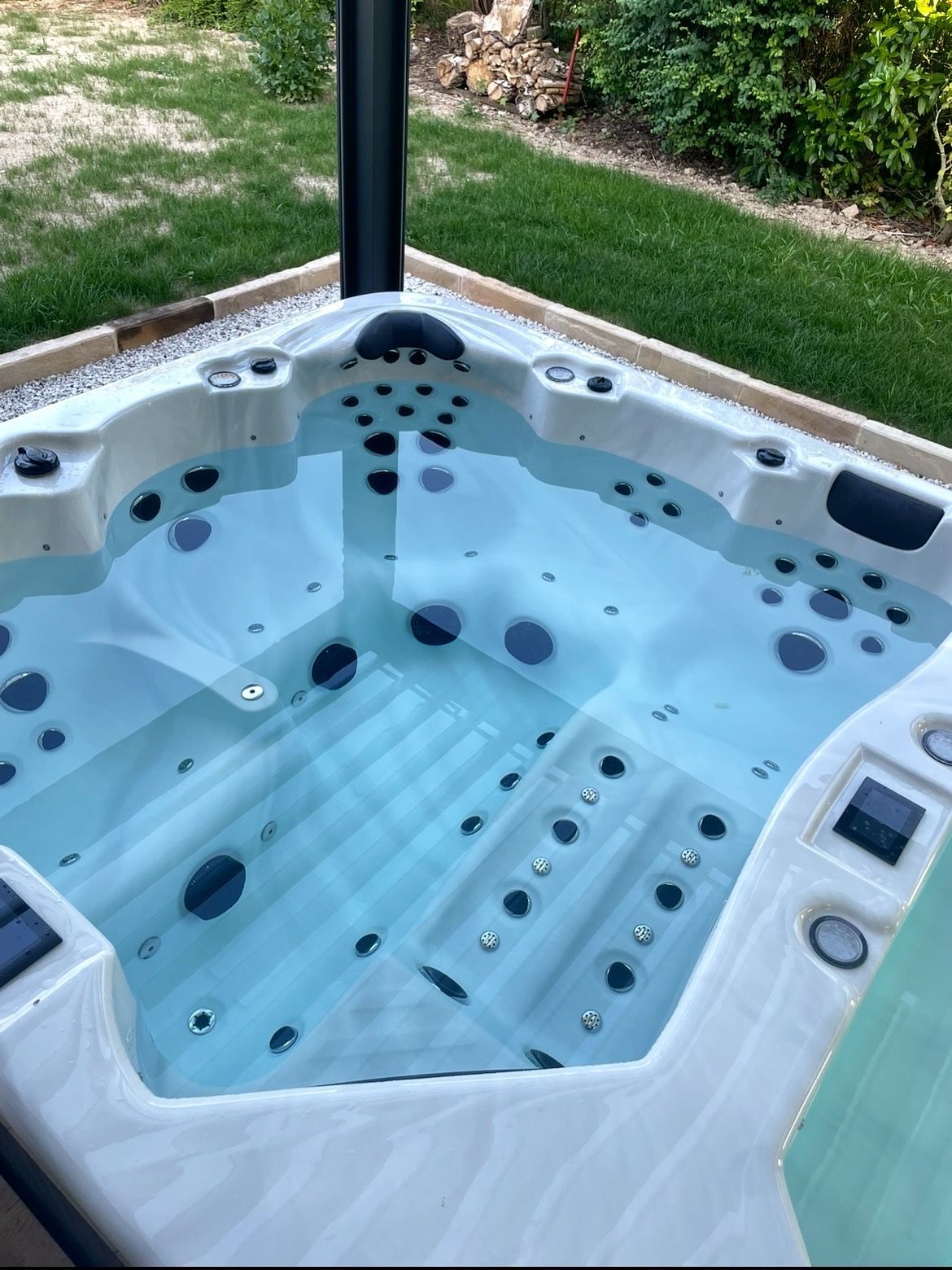 Spa avec eau claire et nombreux jets, extérieur avec gazon vert.