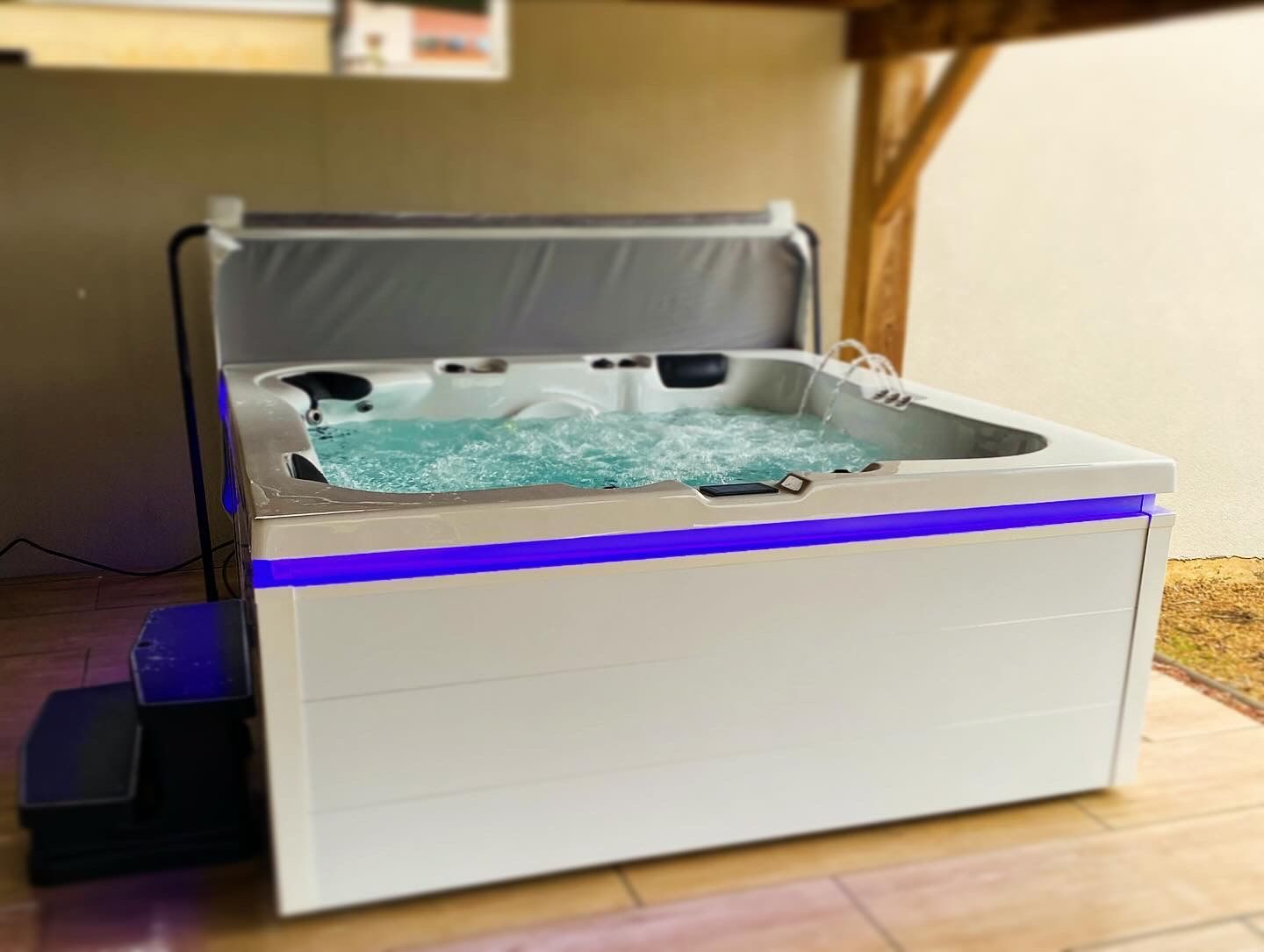 Un jacuzzi blanc avec des lumières bleues est posé sur un sol carrelé.