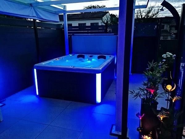 Un bain à remous est éclairé par des lumières bleues sur une terrasse.