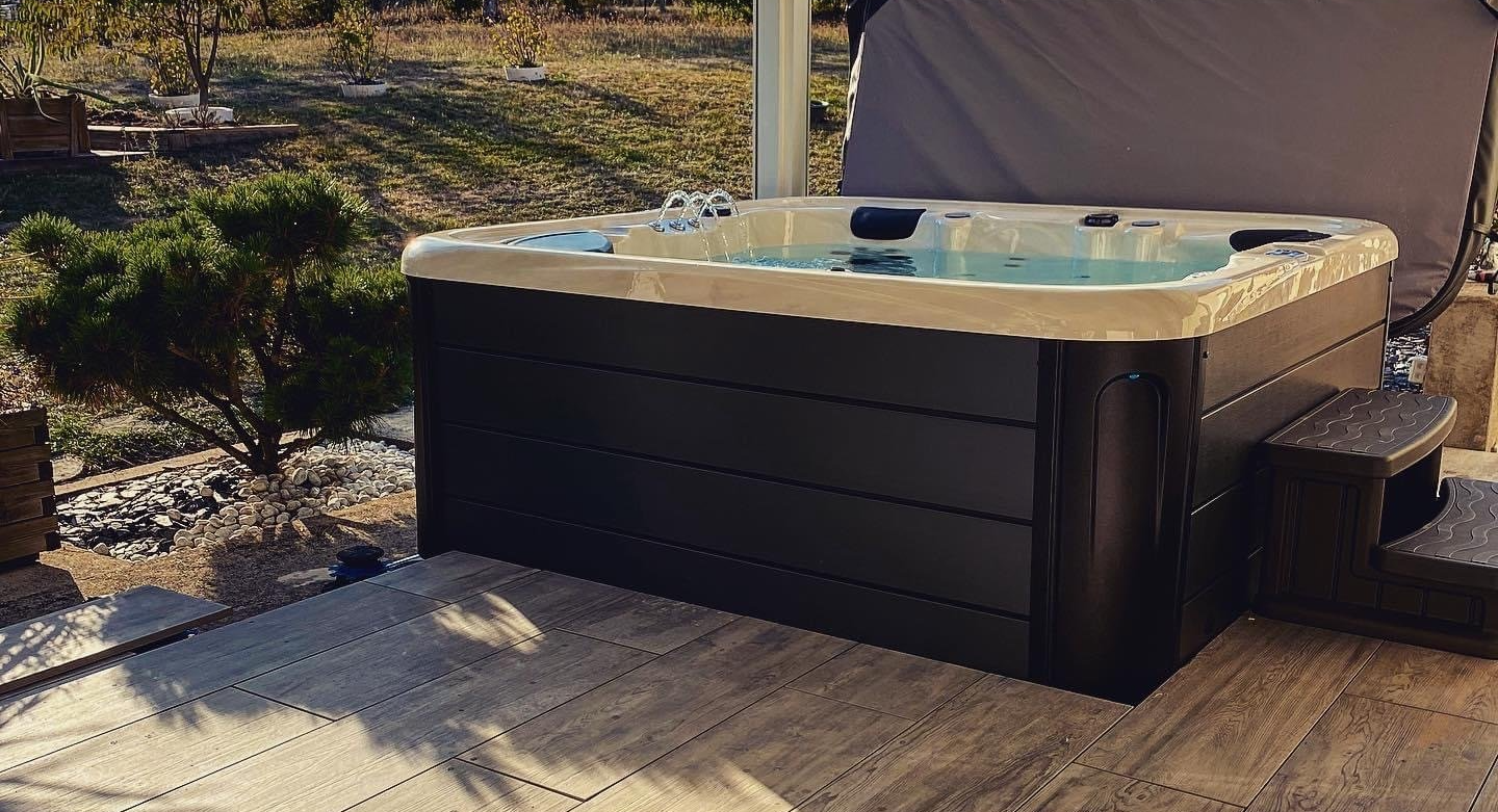 Un bain à remous est posé sur une terrasse en bois.