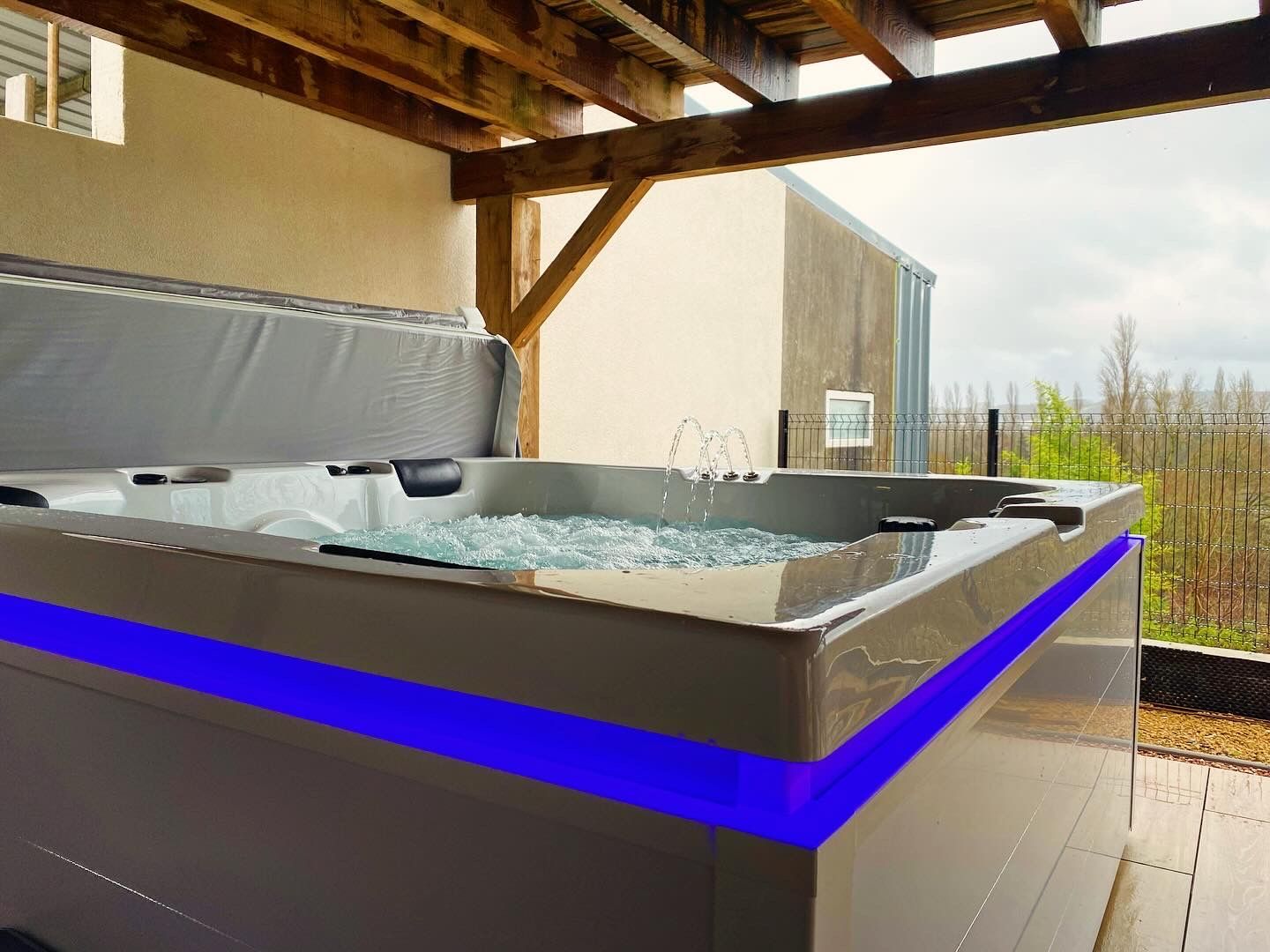 Un bain à remous est installé sous un toit en bois sur une terrasse.