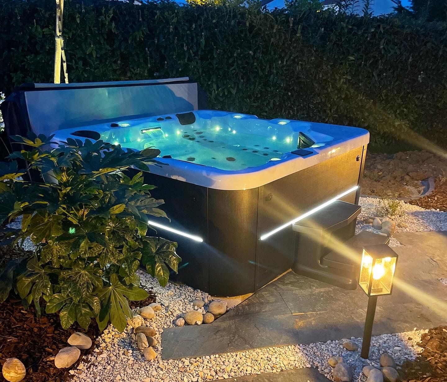 Un jacuzzi est éclairé la nuit dans un jardin