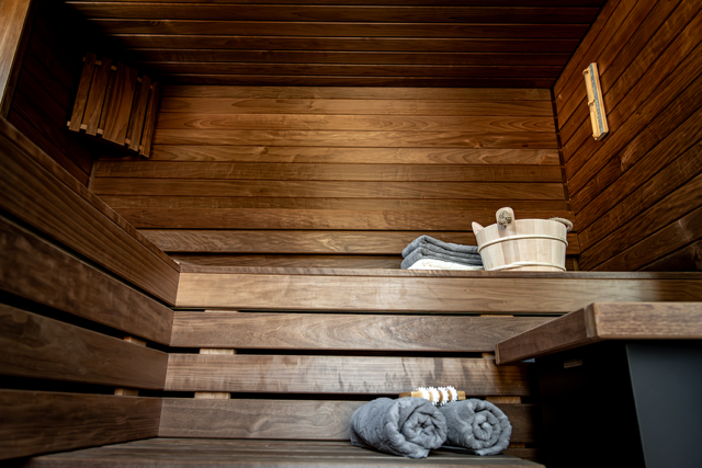 Un sauna en bois avec des serviettes et un seau sur le banc.