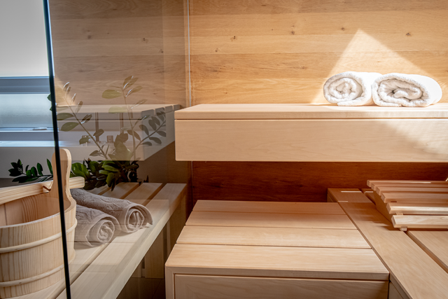 Un sauna en bois avec des serviettes sur une étagère et une porte vitrée.