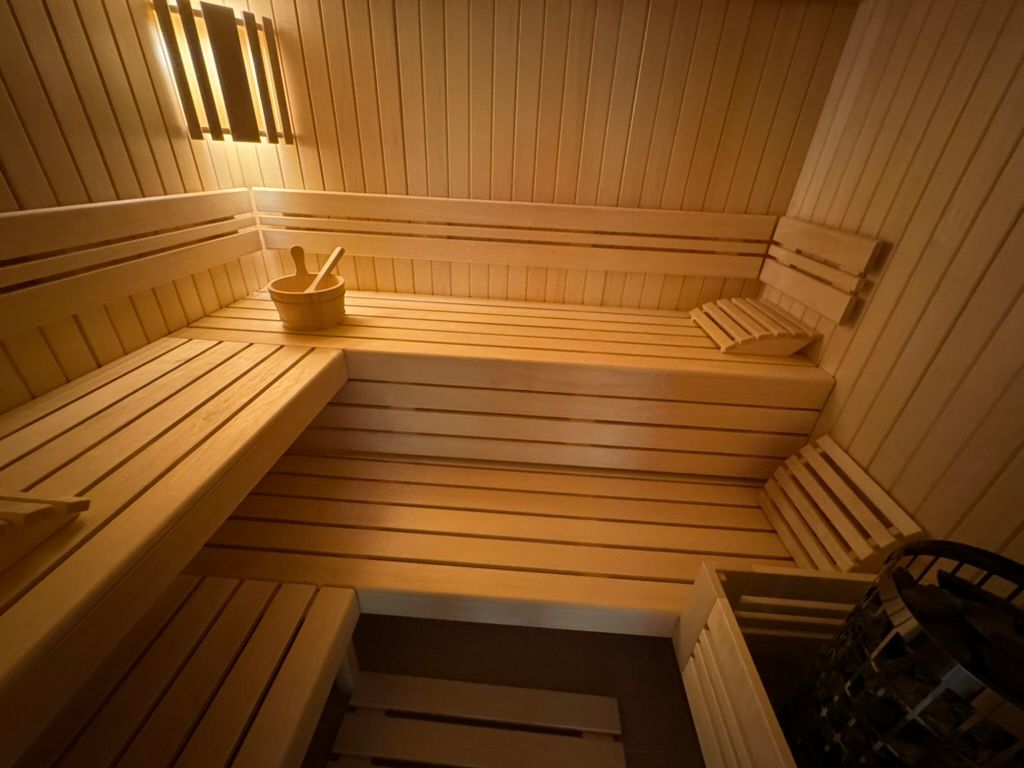 Un sauna en bois avec un seau de brosses sur le banc