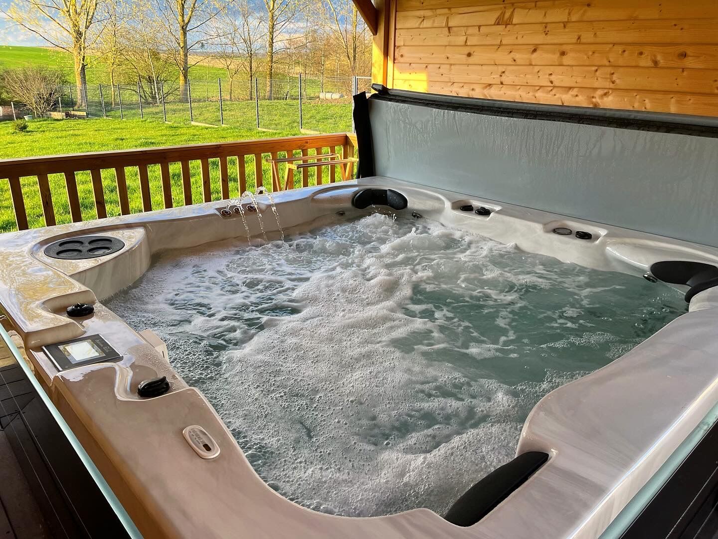 Un grand bain à remous est posé sur une terrasse en bois.