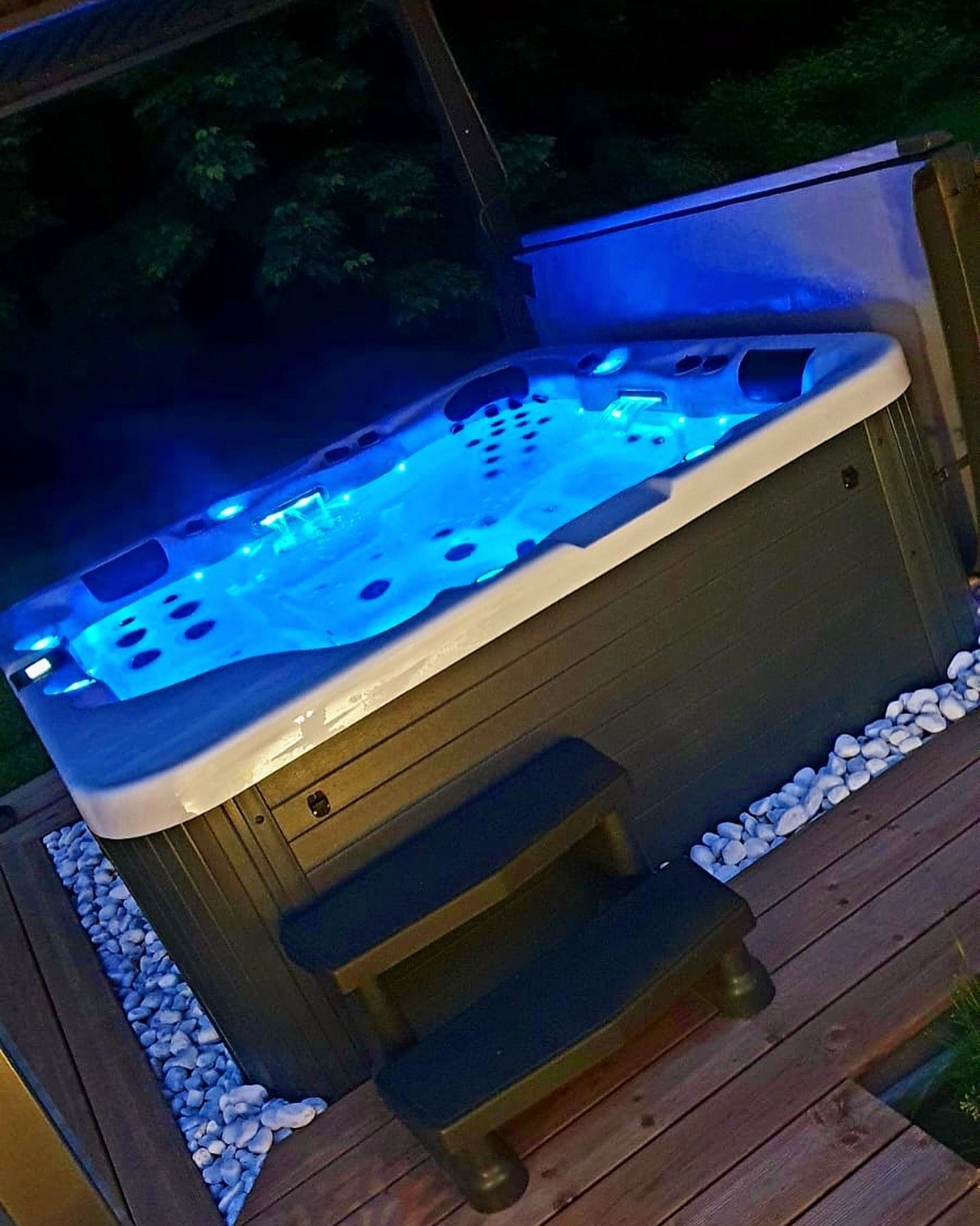 Un jacuzzi avec des lumières bleues se trouve sur une terrasse en bois