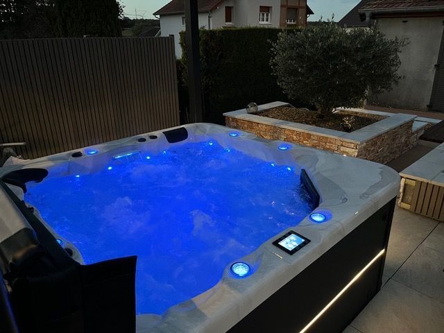 Un bain à remous est éclairé par des lumières bleues dans une cour arrière.