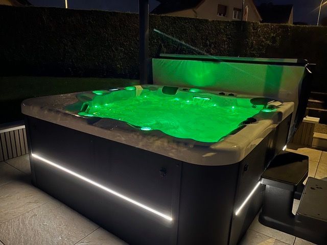 Un bain à remous est éclairé par des lumières vertes la nuit.