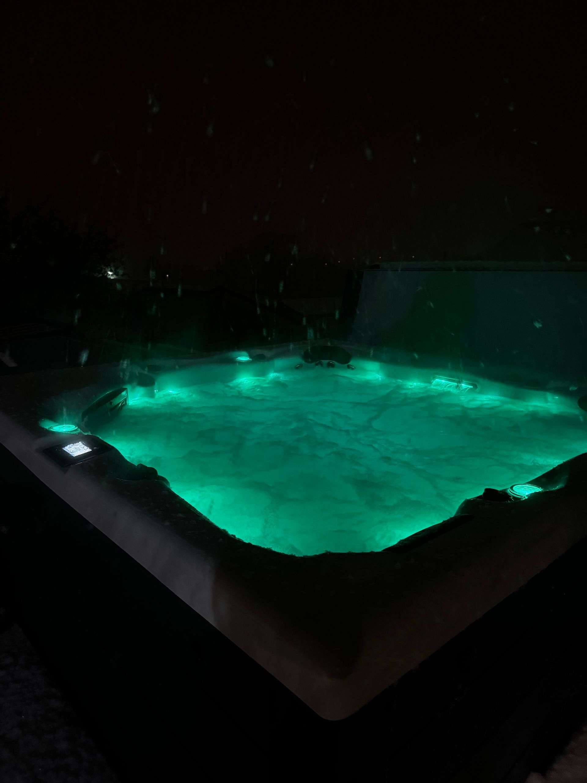 Un bain à remous est éclairé la nuit avec des lumières vertes.