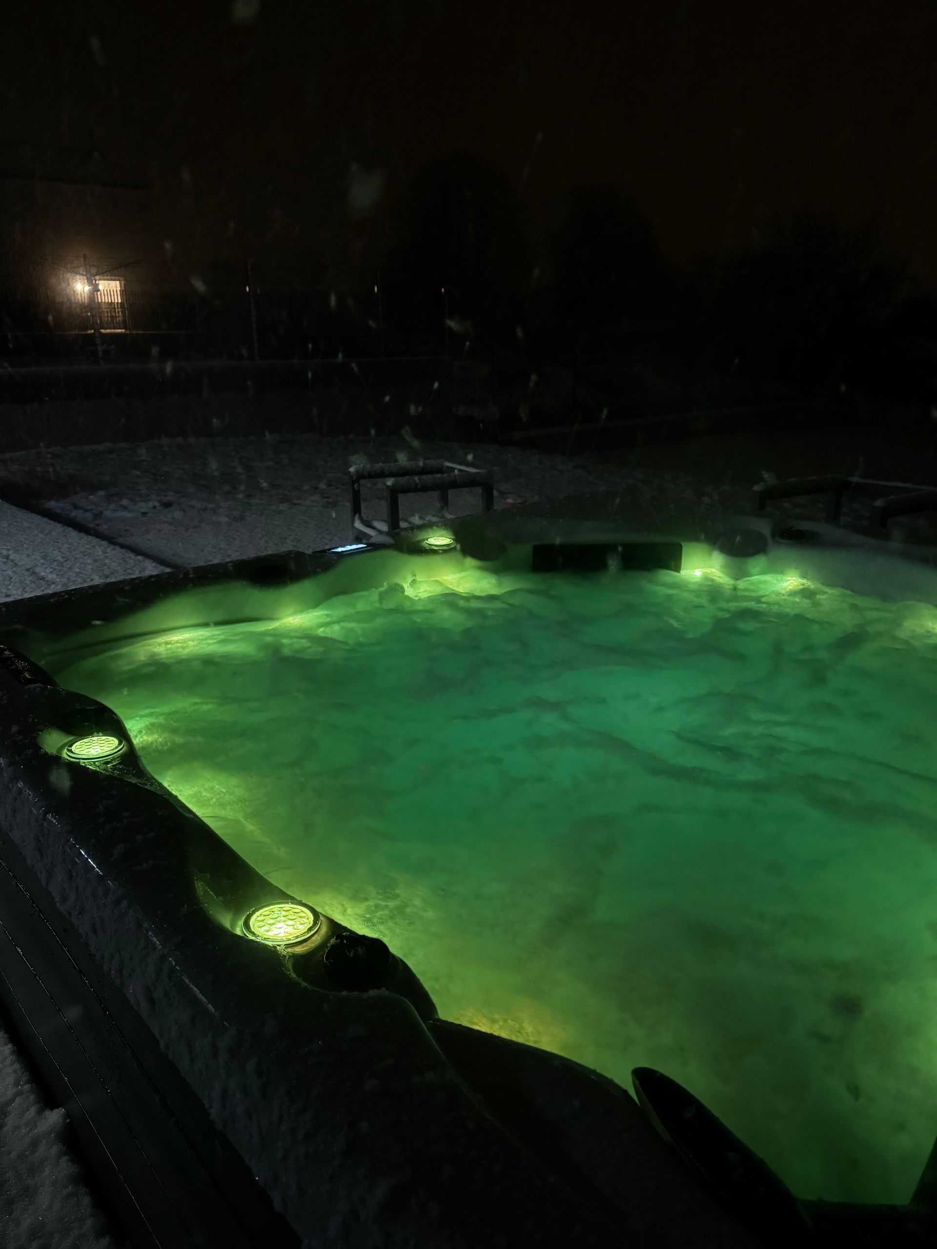 Un bain à remous est éclairé par des lumières vertes la nuit
