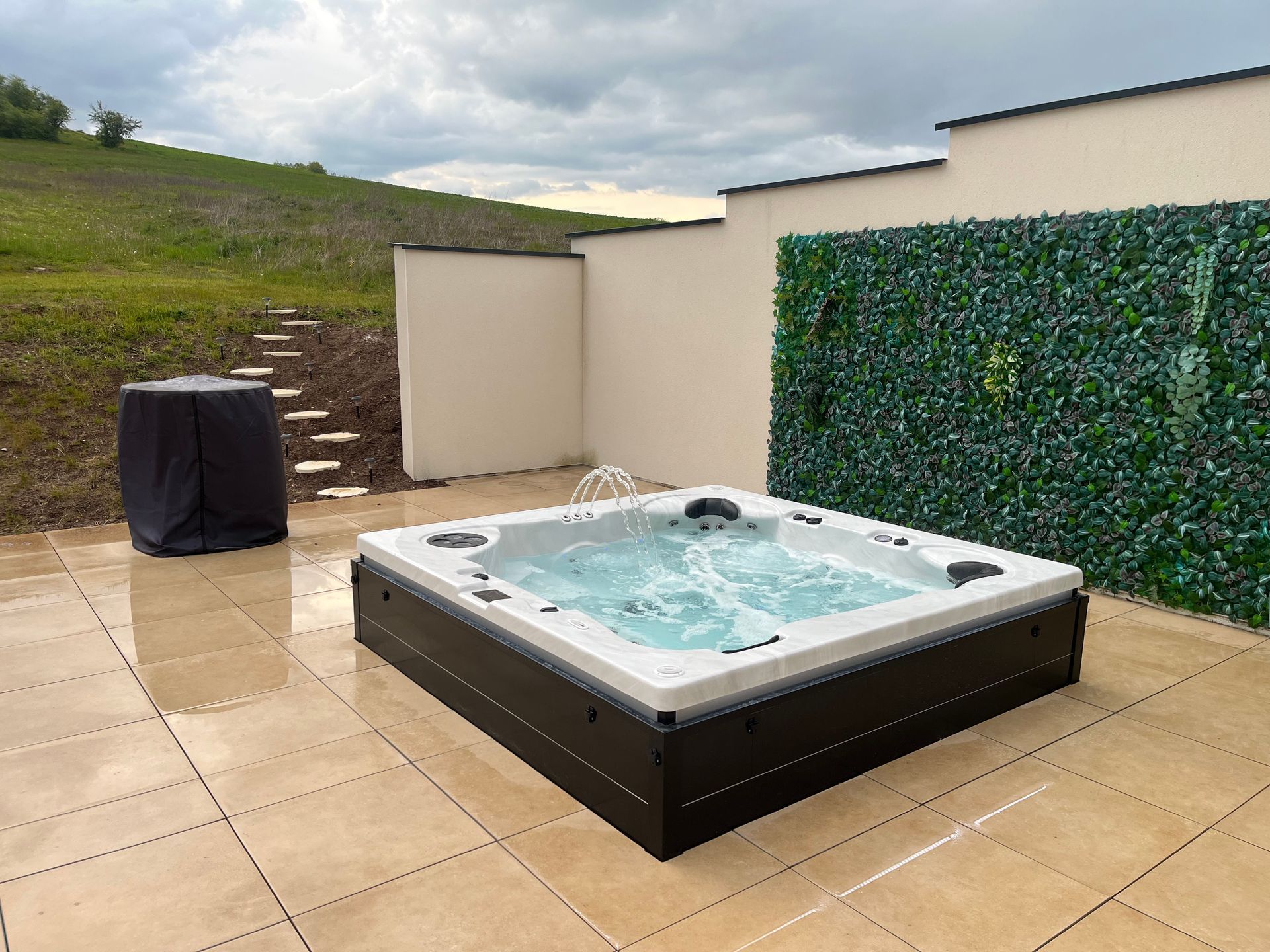 Un bain à remous est installé sur une terrasse carrelée à côté d'un mur.