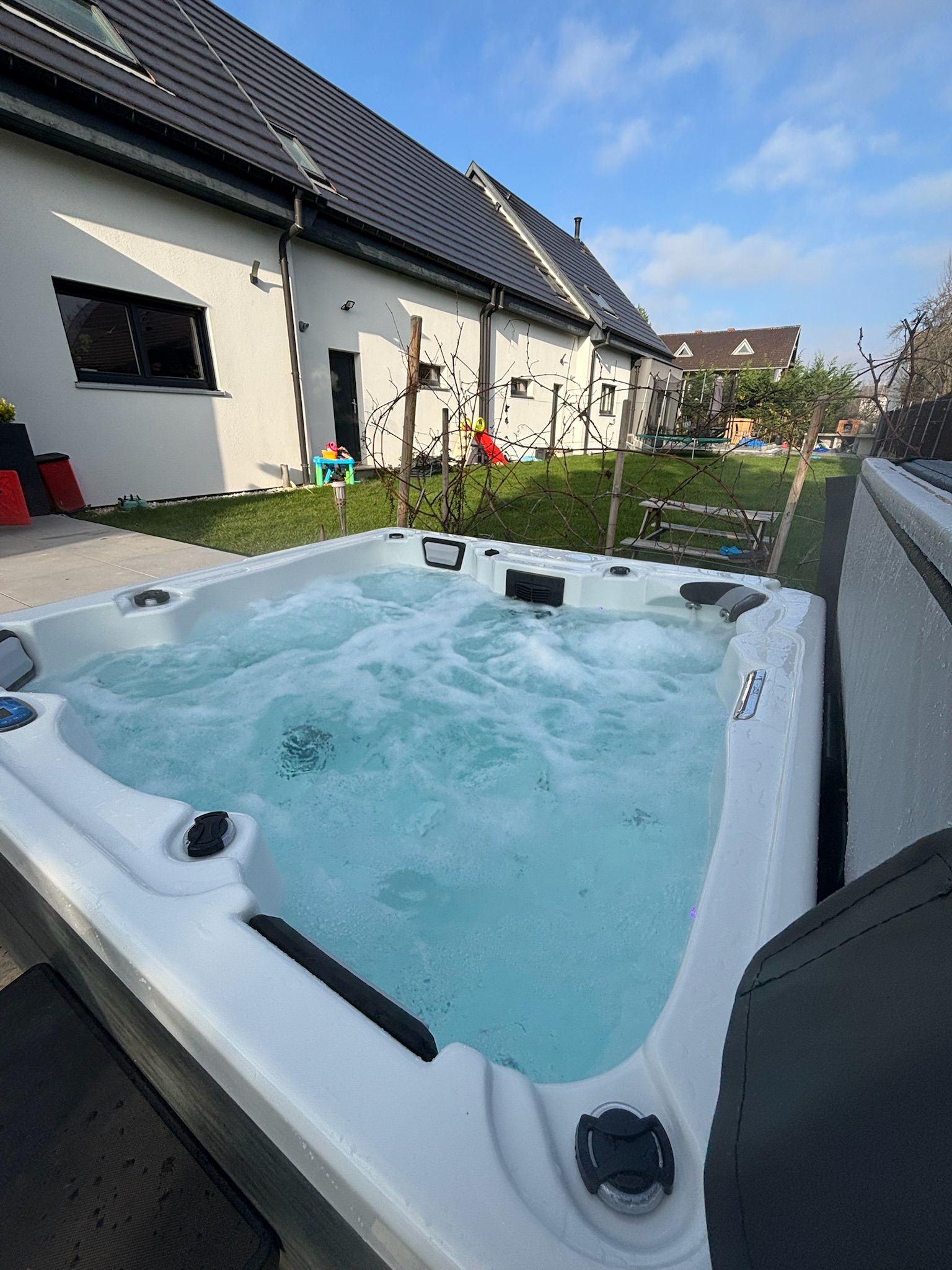 Un grand jacuzzi blanc se trouve devant une maison.