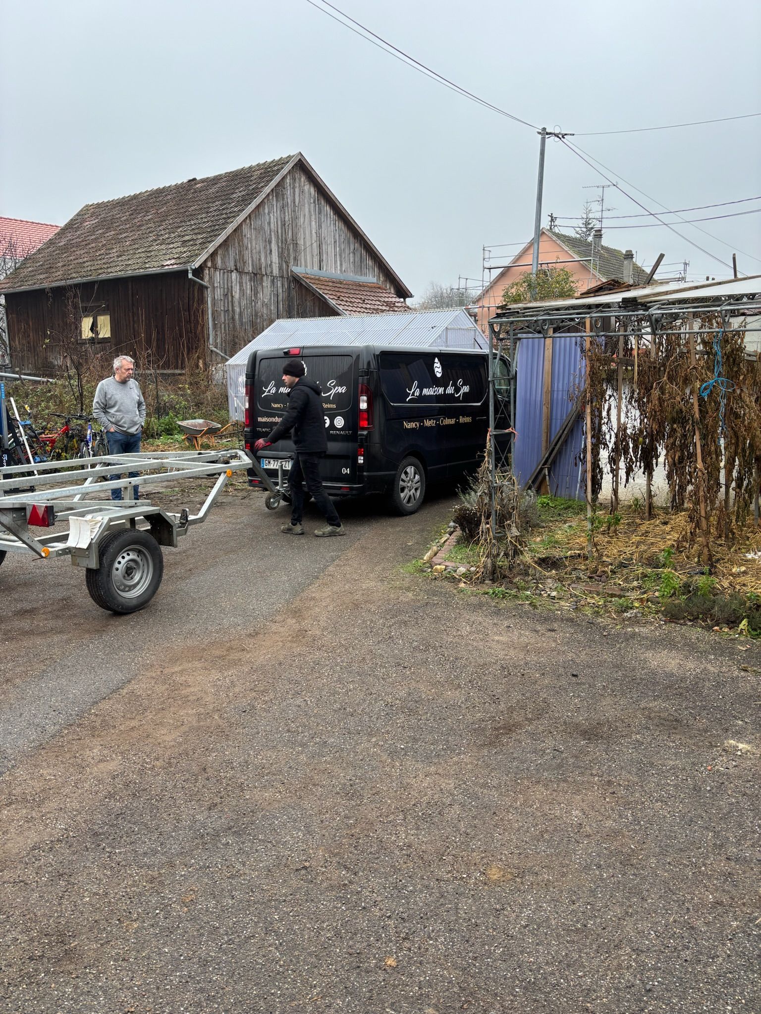 Une remorque est tractée par une camionnette noire sur un parking.